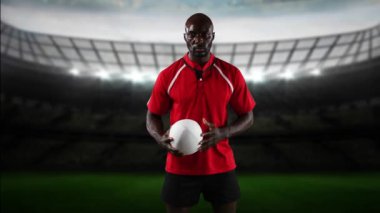 Bir Afro-Amerikan erkek rugby oyuncusu bir top ile oynarken ve arka planda ışıklandırılmış stadyum ile kameraya bakarak Animasyon