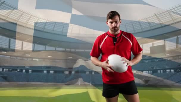 一个白人男性橄榄球运动员玩球的动画 并期待与吹希腊国旗和体育场的背景相机 — 图库视频影像