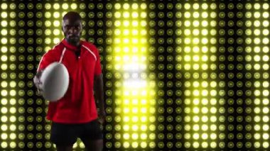 Bir Afro-Amerikan erkek rugby oyuncusu bir top ile oynarken ve arka planda sarı ışıklar hareketli dijital ekran ile kameraya bakarak Animasyon