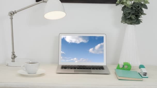 在笔记本电脑屏幕上显示蓝天上的云动画 桌上配有咖啡杯 花瓶和办公材料 — 图库视频影像