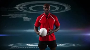Bir Afro-Amerikan erkek rugby oyuncusu ayakta ve bir top tutarak ve tıbbi veri koyu mavi arka plan üzerinde görünen kameraya bakarak Animasyon