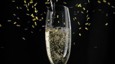 Siyah bir arka plan üzerine düşen altın konfeti ile bir bardağa dökülen şampanya yakın çekim animasyon