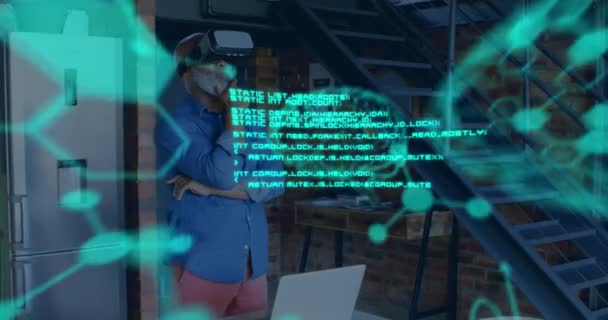 前景に浮かぶ緑の科学データのアニメーション 背景にVrヘッドセットを身に着けている中年の混合人種の男4K — ストック動画