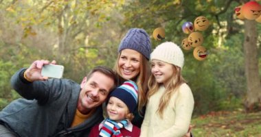 Arka planda, karısı ve kızlarıyla selfie çeken genç beyaz bir adamla sağdan sola uçan emoji simgelerinin animasyonu 4k