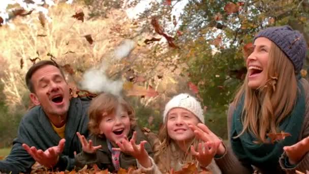 今年秋天 一个白种人家庭在公园里扔树叶时 云彩构成的房子的动画在背后闪烁着 — 图库视频影像