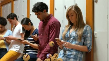 Arka planda akıllı telefonlar kullanan çok ırklı bir grup genç insanla birlikte uçan emoji simgelerinin canlandırılması