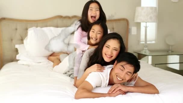 背景にある寝室のベッドの上に アジアの家族が寝そべっている雲の家の形のアニメーション — ストック動画