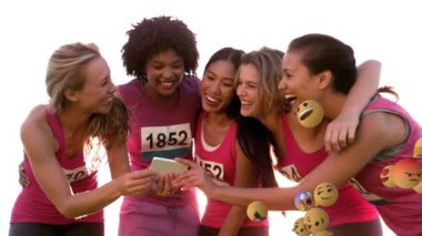 Arkadan sağa sola hareket eden emoji simgelerinin animasyonu ve arka planda bir grup çok ırklı genç kız arkadaşın selfie çekmesi.