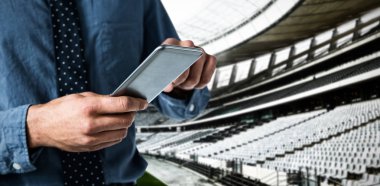 İş adamının şafak vakti ragbi stadyumuna karşı akıllı telefon kullanması.