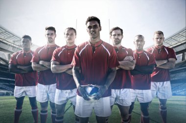 Rugby takımı, güneşli bir günde stadyumda rugby kalesine karşı sahada duruyor.