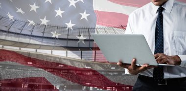 Bir Amerikan bayrağına karşı dizüstü bilgisayar kullanan işadamının orta kesimi