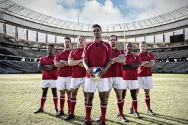 Çeşitli rugby oyuncuları sahada, güneşli bir günde stadyumda rugby kalesine karşı.