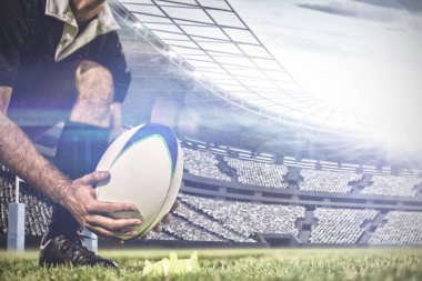 Erkek rugby oyuncusu rugby sahasına karşı stadyumda bir stand üzerinde rugby topu yerleştirerek