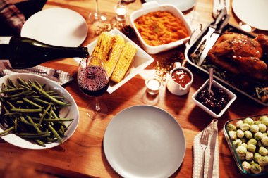 Şükran günü yemeği için belirlenen evde bir masada bir şişe dökülen kırmızı şarap bir bardak yüksek açı görünümü