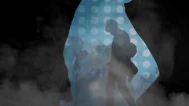 Mavi noktalı arka planda duman bulutlarıyla dans eden bir grup siluetli insanın animasyonu