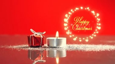 Sarı harflerle yazılmış mutlu noeller ve parıldayan kalp şeklinde yuvarlak bir çerçeveyle yazılmış peri ışıkları Noel hediyesi ve kırmızı arka planda çay ışığı.