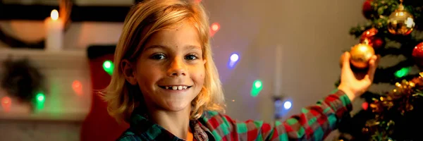 クリスマスの時期に居間にクリスマスツリーを飾る若い白人少年の肖像画 カメラに微笑む — ストック写真