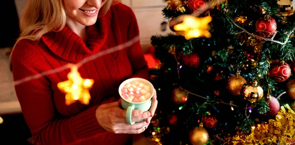 一个年轻的白人女人在圣诞节的时候把杯子放在客厅里 前面挂着圣诞明星的装饰品 这是一张高视角的照片 — 图库照片