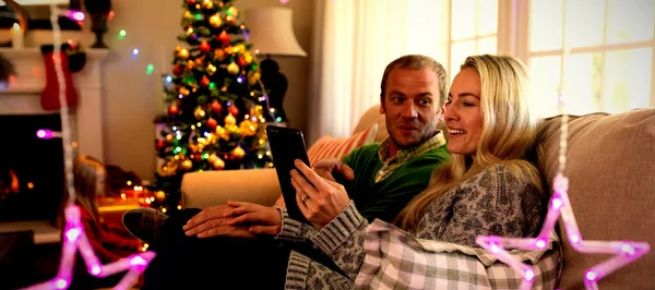 크리스마스 시간에 자신의 거실에서 태블릿을 사용하여 부부의 측면보기 — 스톡 사진