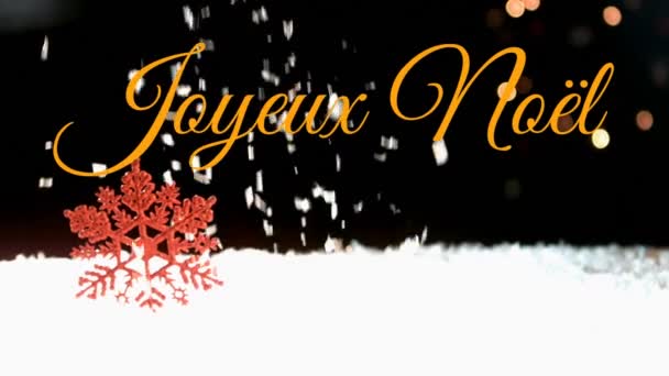 背景に降る雪の上にオレンジで書かれたジョワウ ノエルという言葉のアニメーション — ストック動画