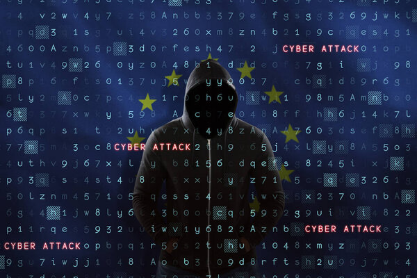 Male hacker in black hoodie standing against close-up of European flag