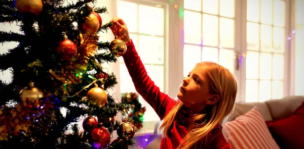 クリスマスの時期に彼女の居間にクリスマスツリーを飾る若い白人の女の子の側面図 — ストック写真