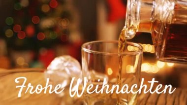 Beyaz ile yazılmış Frohe Weihnachten kelimelerinin animasyonu. Arka planda Noel ağacı ile birlikte içki dökülüyor.