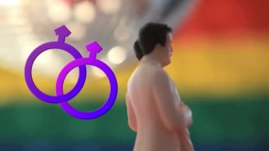 İki birleşmiş mor erkek sembolü ve birbirine sarılan pembe kravatlı ve beyaz takım elbiseli iki erkek heykelciğin bulanık disko topuna ve çizgili arka plana doğru dönüşmesi.