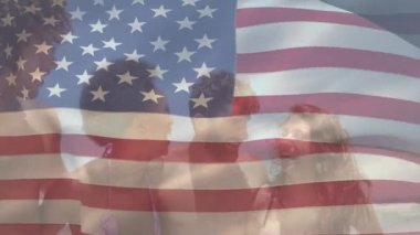 Sahilde duran çok ırklı arkadaş grubunun üzerinde Amerikan bayrağının dalgalanması. Amerika Birleşik Devletleri bayrağı ve tatil konsepti dijital kompozisyon