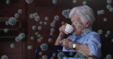 Kafkasyalı yaşlı bir kadının tekerlekli sandalyede oturup bir fincan kahve içtiği makro Covid-19 hücrelerin animasyonu. Coronavirus Covid-19 pandemik konsept dijital bileşik