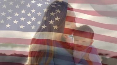 Beyaz bir kadının bebeğini kafasından öptüğü ve sahilde dikildiği Amerikan bayrağının animasyonu. Amerika Birleşik Devletleri bayrağı ve tatil konsepti dijital kompozisyon
