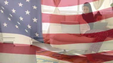 Birleşik Devletler bayrağının karışık ırktan bir kadın ve kızının teknolojik aletler kullanarak koltukta oturmasının animasyonu..