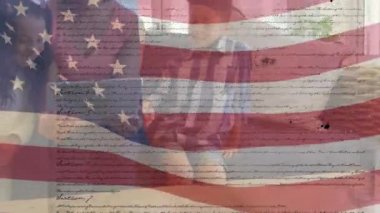 ABD bayraklarının ABD Anayasası metniyle dalgalanması çocuklarıyla birlikte tablet kullanan melez bir kadının üzerine yuvarlanması.. 