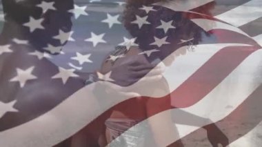 Karışık ırktan bir adamın sevgilisine sahilde masaj yaptığı Amerikan bayrağının animasyonu. Amerika Birleşik Devletleri bayrağı ve tatil konsepti dijital kompozisyon