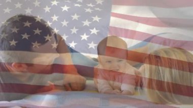 Beyaz bir çiftin bebekleriyle oynadığı Amerikan bayrağının animasyonu. Amerika Birleşik Devletleri bayrağı ve tatil konsepti dijital kompozisyon