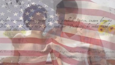 Amerikan bayrağının ABD Anayasası metniyle dalgalanması karışık ırk çiftlerinin kucaklaşması. Amerika Birleşik Devletleri bayrağı ve tatil konsepti dijital kompozisyon