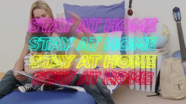 カラフルなネオンの言葉の4行のアニメーションは 彼女の子供たちに本を読んで白人女性の上に家に滞在します 公衆衛生パンデミックコロナウイルスクアルンのCovid 19社会的距離と自己分離 — ストック動画