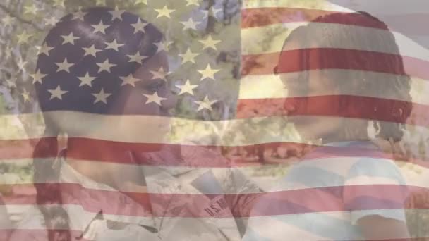 アメリカ国旗のアニメーションは 複雑な人種の女性兵士が息子と話す上で手を振っている 米国の国旗と休日のコンセプトデジタル組成物 — ストック動画