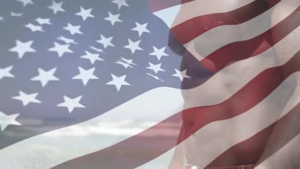 Animacja Amerykańskiej Flagi Machającej Nad Afroamerykaninem Chodzącym Plaży Bez Koszulki — Wideo stockowe