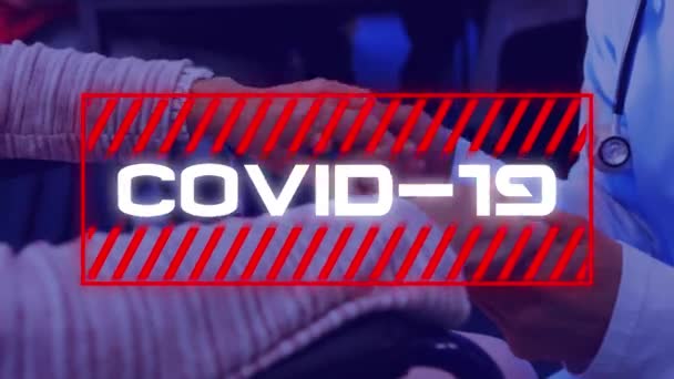 女性看護師の手を握って車椅子に座っている女性の上に赤い枠で単語Covid 19のアニメーション コロナウイルスCovid 19パンデミックコンセプトデジタル複合体 — ストック動画