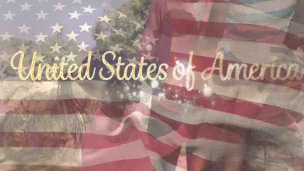 アメリカ国旗のアニメーションがアメリカのテキストで手を振って 庭で遊んでいる混合人種の家族の上に花火 米国の国旗と休日のコンセプトデジタル組成物 — ストック動画