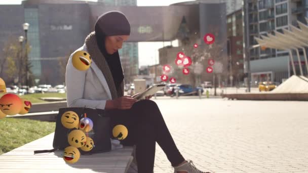 Duvarda Oturmuş Yüzen Emojilerin Üzerinde Tablet Kullanan Melez Bir Kadının — Stok video
