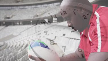 Afrika kökenli Amerikalı erkek rugby oyuncusunun elinde dijital bir top tutarak saatinin işlemesi
