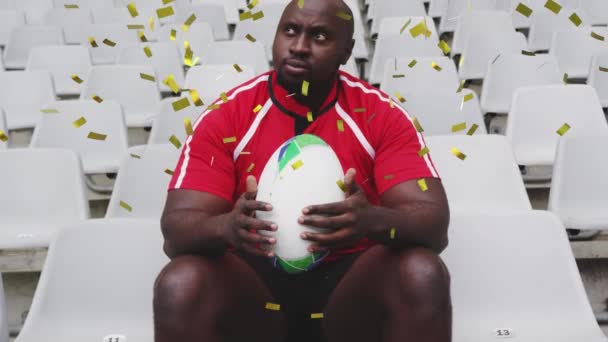 Animatie Van Gouden Confetti Vallen Afro Amerikaanse Mannelijke Rugbyspeler Zitten — Stockvideo