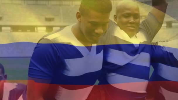 一支哥伦比亚国旗飘扬在由多个种族的男子橄榄球队组成的数字组合上 — 图库视频影像
