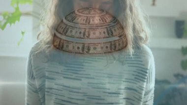 Beyaz kadın maske dikerken dönen Amerikan dolarlarından oluşan bir dünyanın animasyonu. Coronavirus Covid-19 konsept dijital kompozisyon