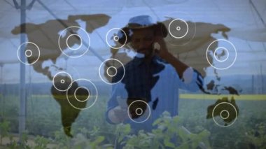 Dünya haritasında titreşen simgelerle bağlantıların animasyonu ve akıllı telefon kullanan bir adam. Genel bağlantı ağı konsepti dijital bileşik.