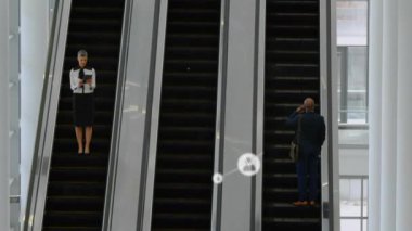 Modern bir ofiste yürüyen merdivenlerle konuşan kadın ve erkeğin arayüz simgeleriyle olan bağlantıların animasyonu. Genel bağlantı ağı konsepti dijital bileşik.