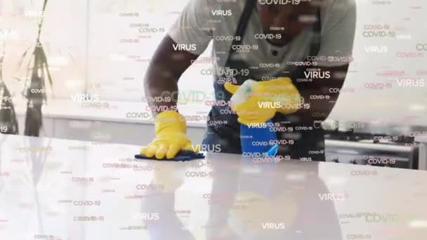 Covid 19单词的动画漂浮在非裔美国人的头上 他在家里打扫卫生 还拿着洒水器 Coronavirus Covid 19大流行病概念数字组合 — 图库视频影像