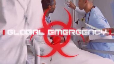 Kırmızı biyolojik tehlike ikonunun animasyonu beyaz kelimelerle Küresel Ortaya çıkıyor ve arka planda melez kadın hasta ve tıbbi personel var. Coronavirus Covid-19 pandemik konsept dijital bileşik.